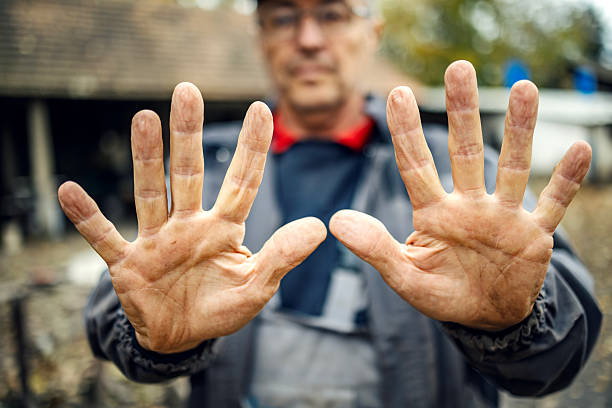 Senior man showing a clear stop gesture with both dirty hands, rejecting something with a serious expression