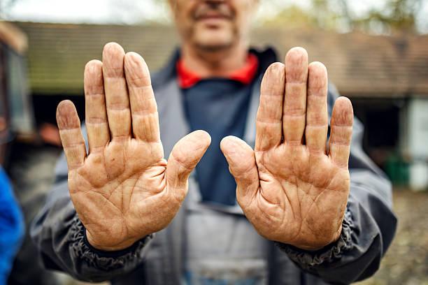 Mature adult man showing his palms, both hands dirty and calloused from manual labor, signaling a stop gesture