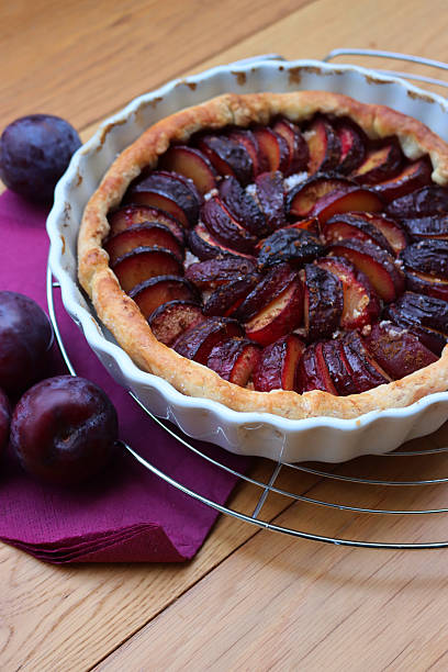 istock Cake or tart with sliced purple plums on a cooling rack on table 2245442675