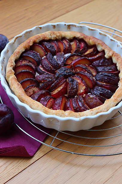 istock Cake or tart with sliced purple plums on a cooling rack on table 2245442738