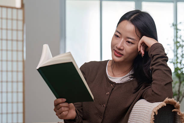 istock Focused Reading. Woman deeply engaged in a book while relaxing at home. 2245446705