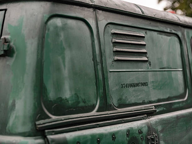 Weathered green vintage commercial van showing windows ventilation grill and identification number with aged patina
