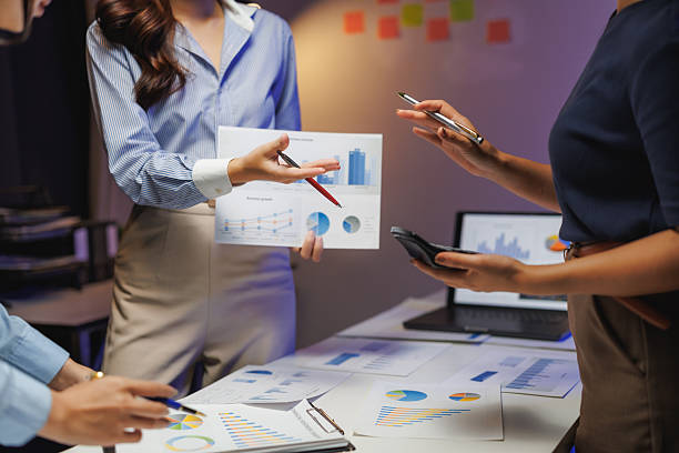 istock Businesswomen discussing financial charts and data at night 2245452351