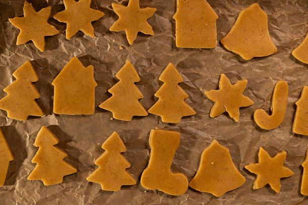 Brightly colored gingerbread cookies shaped like stars, trees, and houses are laid out on parchment paper. These cookies bring joy and tradition to the Christmas season.