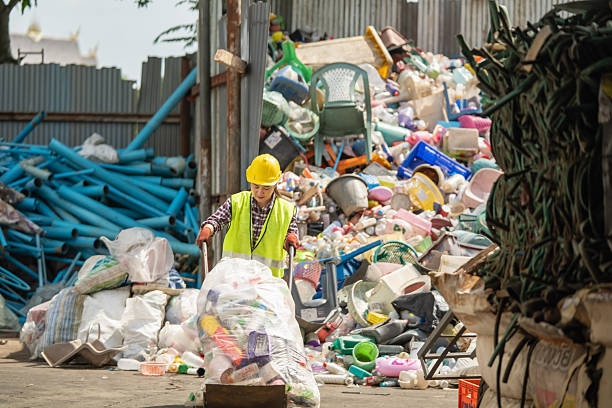 An Asian woman uses a cart to pull and sort trash for recycling.