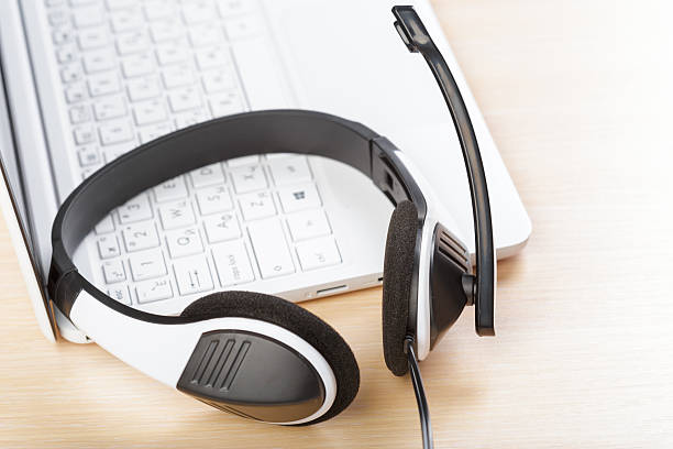 istock Headset placed next to a laptop on a wooden desk during daytime 2245456447