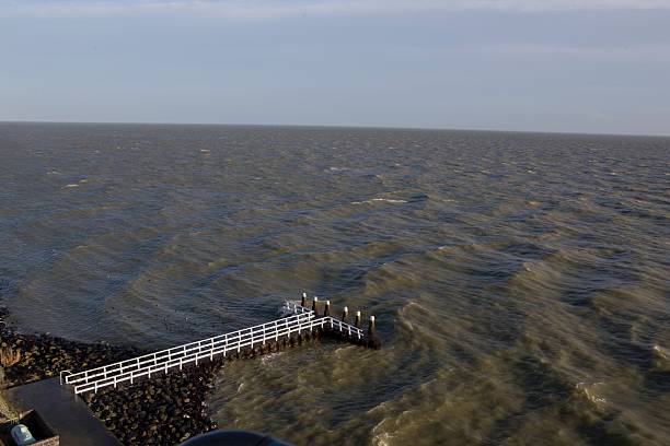 The Afsluitdijk is a remarkable 32-kilometer-long dam in the Netherlands that connects provinces of North Holland and Flevoland. IJsselmeer. Pier and IJsselmeer view