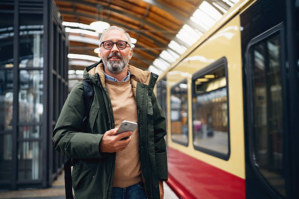 istock Cheerful Middle-Aged Man with Eyeglasses Standing at a Berlin Hackescher Markt Train Station as a Train Approaches 2245458452