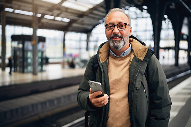 istock Portrait of a Smiling Middle-Aged Man Standing at a Train Station in Berlin While Holding a Smart Phone 2245458533