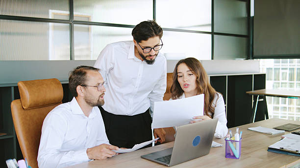 istock Three colleagues collaborate on a project, reviewing documents together at a well-organized desk in a contemporary office environment. 2245458584