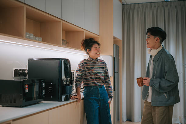 istock Two Young Chinese Colleagues Talking in Office Pantry During Coffee Break 2245462733