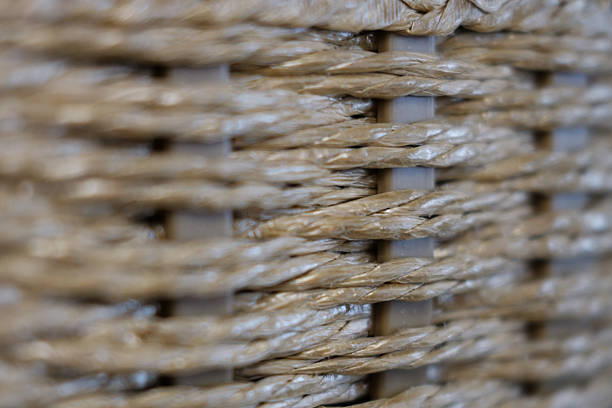 Macro close-up of a woven wicker or rattan texture. The focus highlights the intricate, handmade craftsmanship and natural fibers. Shallow depth of field creates a soft, abstract background.