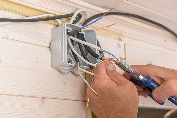 istock Closeup of electrician twisting copper wires together inside open junction box, assembling electrical system in wooden house. 2245464891