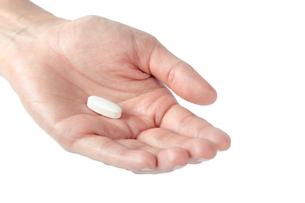 istock Hand holds a small white pill in a clean, bright setting during a health moment 2245466915