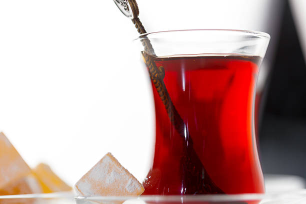 Red tea is served in a clear glass with ice cubes, perfect for a hot afternoon treat.