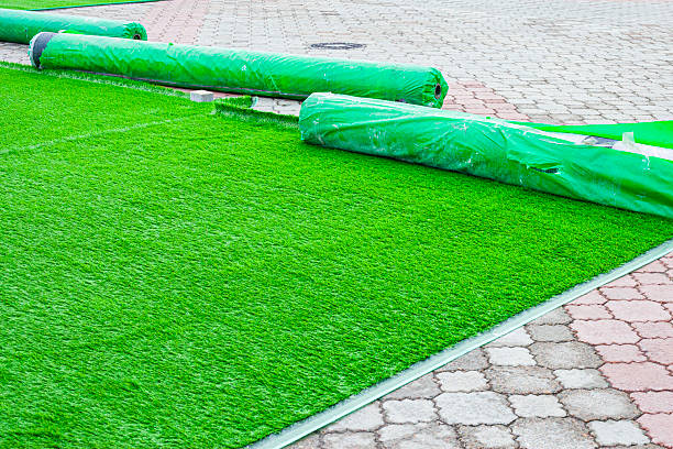 istock Laying and installing artificial green grass on old paving slabs is a temporary solution for landscaping. 2245468781