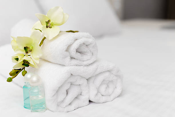 istock Elegant bathroom setup with rolled towels and decorative flowers on a bed 2245469049