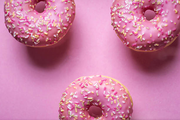 Pink Frosted Doughnuts with Sprinkles on a Pink Surface