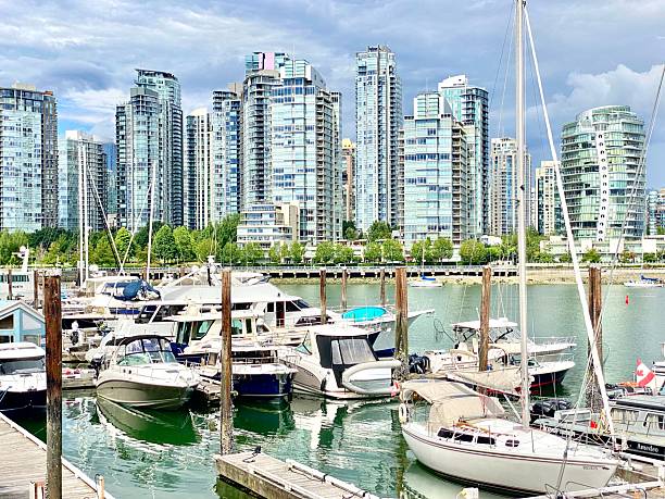 Vancouver, Canada – July 14, 2025: Scenic view of a marina with yachts and modern skyscrapers in Vancouver, Canada, under a cloudy sky.