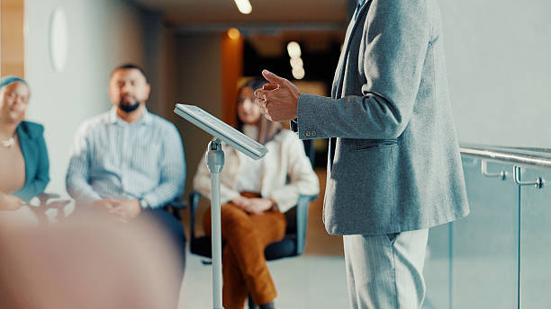 istock Podium, speaker and hands with audience at conference, workshop or symposium for skill development. Corporate talk, presenter person with discussion or keynote speech at upskill seminar in business 2245470012