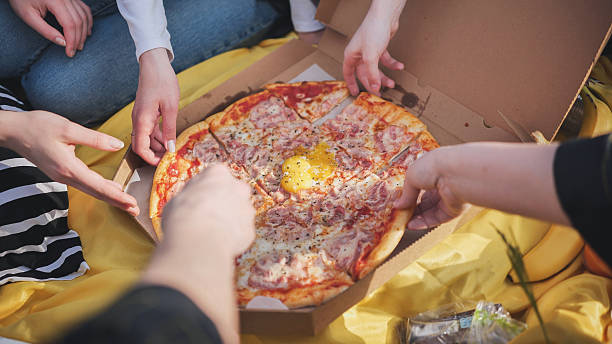 istock A group of hands reach for the pizza. 2245473628