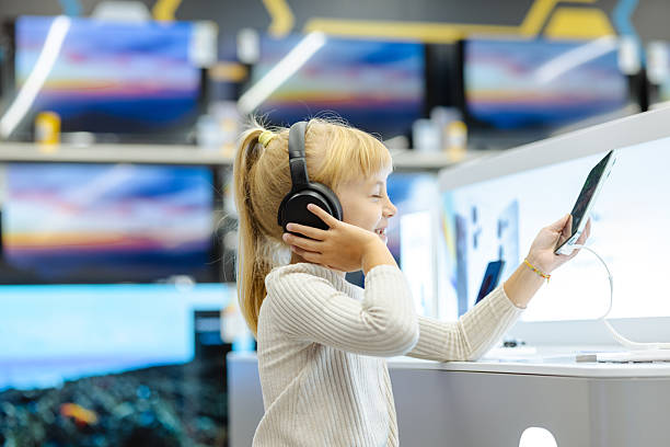 istock Young girl with headphones using a tablet in an electronics store, smiling and exploring devices 2245473718