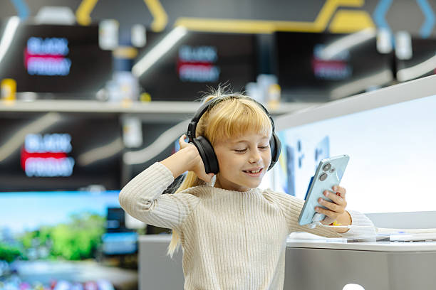 istock Cute girl exploring smartphones in a modern tech store during Black Friday 2245473720