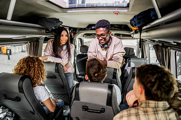 istock Diverse young adults enjoying road trip inside bus 2245473827