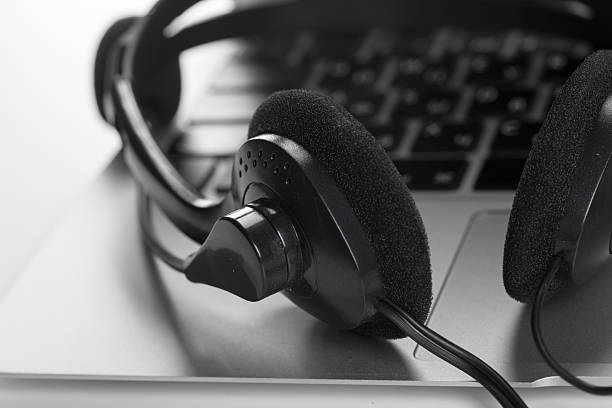 istock Black headphones resting on a silver laptop keyboard in a modern workspace setting 2245473894