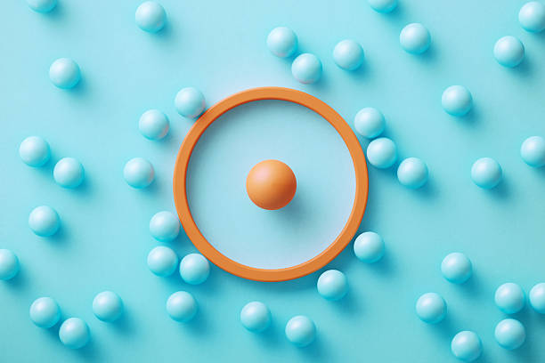 Blue spheres gravitated towards an orange colored target symbol on blue background. Business target and target market concept.