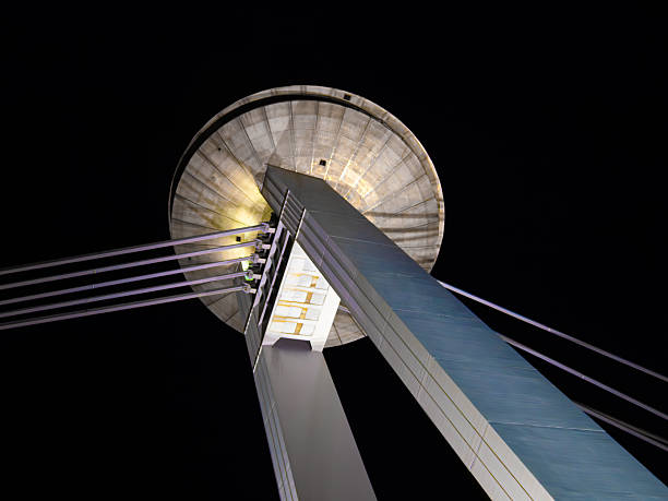 Night view of a modern illuminated suspension bridge in Bratislava with a UFO-shaped observation deck
