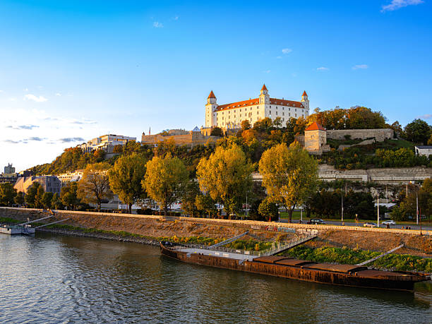 Bratislava, Slovakia - October 18, 2025: Bratislava Castle on a hill with autumn trees and river
