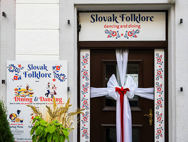 Bratislava, Slovakia - October 21, 2025: A decorative entrance to a restaurant named Slovak Folklore, featuring a sign for dining and dancing, adorned with floral patterns and a white ribbon