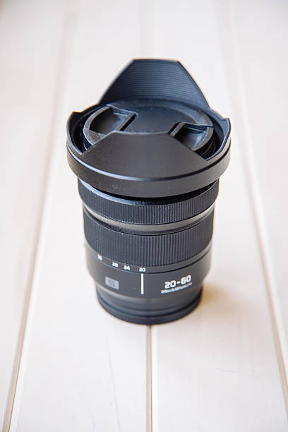 istock Modern digital camera lens standing on white wooden desk 2245480107