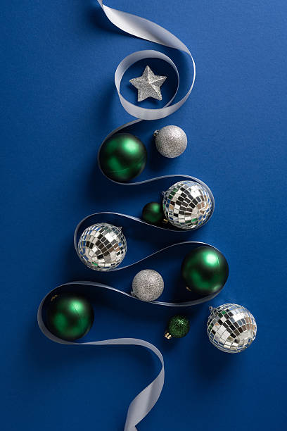 istock Vertical holiday scene with silver ribbon weaving between green and silver ornaments, evoking Christmas and New Year celebration 2245480491