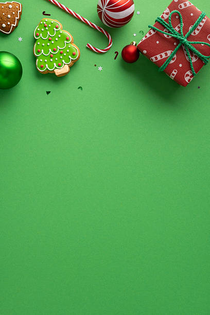 istock A bright vertical holiday scene features green cookie with icing, candy canes, a red wrapped gift, and scattered confetti against a vivid green backdrop, capturing festive mood seasonal celebration 2245480493