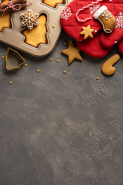 istock A vertical festive scene featuring cookie dough, a muffin tin with cutout shapes, gingerbread stars, a red oven mitt, and candy canes, capturing holiday baking, warmth, and seasonal celebration 2245480518