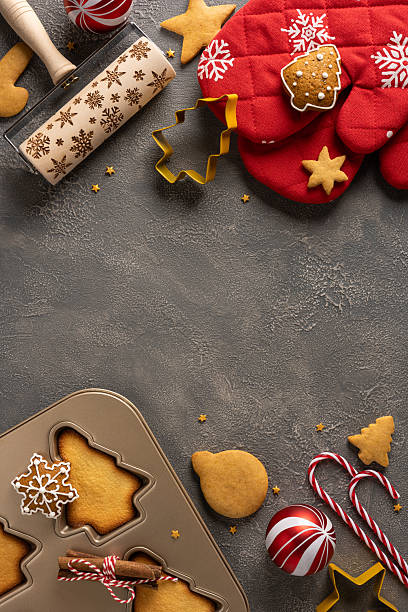 istock A vertical cozy Christmas baking setup with gingerbread shapes, snowflake cookie, star decorations, a tree shaped mold, candy canes, and a red quilted glove that captures warm holiday mood 2245480526