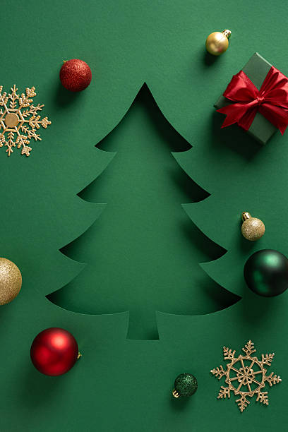 istock A green card features a festive Christmas tree cutout surrounded by ornaments and a gift box, conveying a warm holiday mood and NewYear greeting 2245480547
