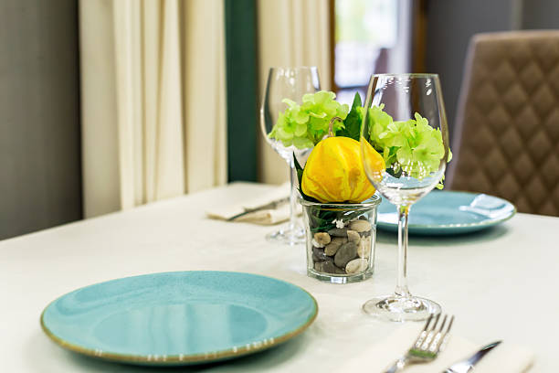 Table set with stylish dishes, glasses, and a beautiful centerpiece featuring flowers and fruit.