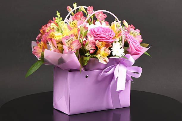 istock A bouquet and a violet bag with handles black background. Bouque 2245483575