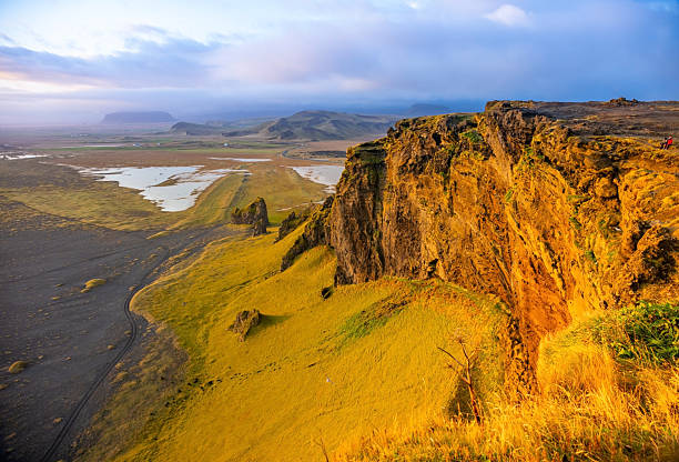 Witness the breathtaking sunset illuminating the Dyrholaey cliffs and Vik beach. The black sand shoreline stretches along the Atlantic, creating a stunning scene in Iceland