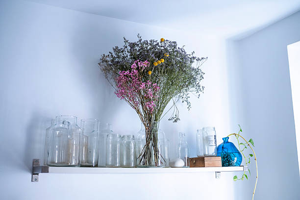 istock Dried flower bouquet and glass jars decorating white shelf 2245488051