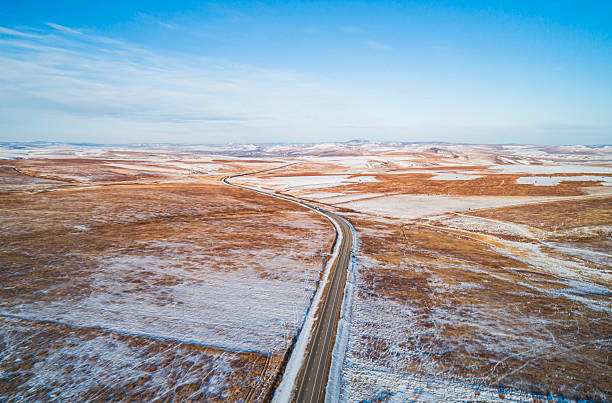 istock Expansive winter landscape featuring a winding road through snow-covered fields under clear blue skies 2245491855
