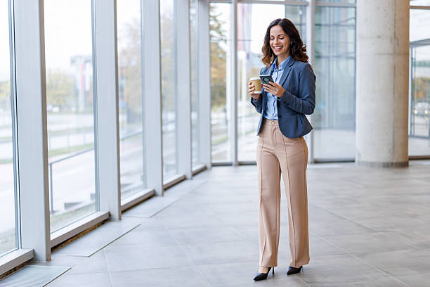 istock Businesswoman checking phone while walking in office building 2245492645