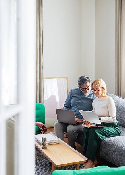 istock Older Couple Working Together at Home on Sofa With Laptop and Documents 2245493636