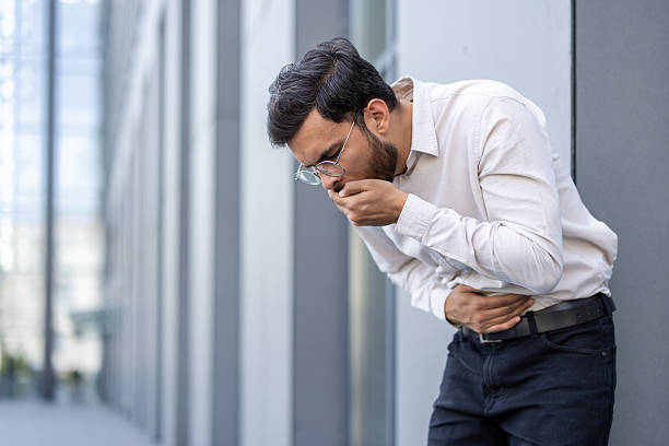 istock Man outdoors experiencing nausea while clutching stomach and coughing 2245494702