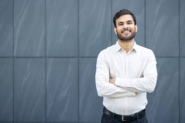istock Confident man standing against gray wall with arms crossed and smiling 2245494723