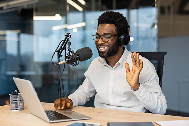 istock Smiling man recording podcast with microphone and laptop in modern office 2245496712