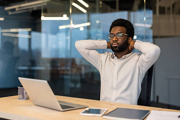 istock Businessman relaxing at desk with hands behind neck in modern office 2245496763